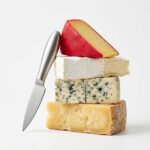 A silver 6-piece RWIXR cheese knife set neatly arranged, featuring various knives, spreaders, and a fork.