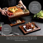 Square acacia wood charcuterie board with ceramic dishes and stainless steel cheese knives, ready for serving.