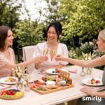 SMIRLY large bamboo charcuterie board set with cheese knives, ceramic bowls, and fruit tray, beautifully arranged with food.