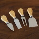 A four-piece Totally Bamboo cheese tool set with brown bamboo handles and silver stainless steel blades, arranged on a surfac
